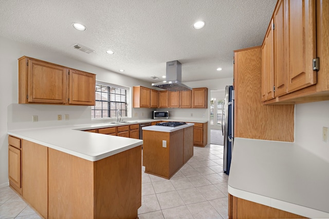 kitchen featuring visible vents, island exhaust hood, stainless steel appliances, a peninsula, and light countertops