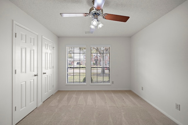 interior space with light carpet, visible vents, a textured ceiling, and baseboards