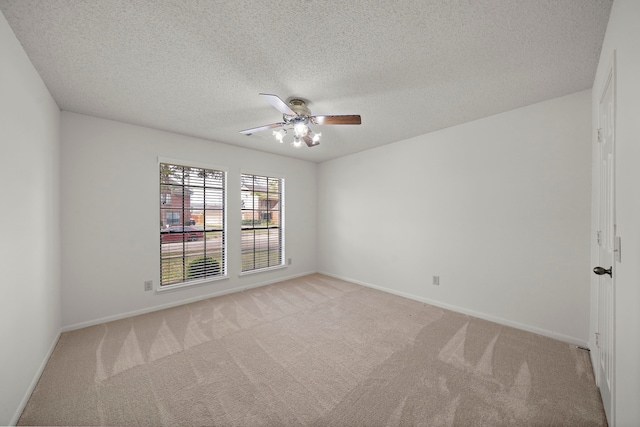 unfurnished room with baseboards, light carpet, a textured ceiling, and a ceiling fan