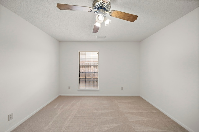 spare room featuring visible vents, baseboards, light carpet, a textured ceiling, and a ceiling fan