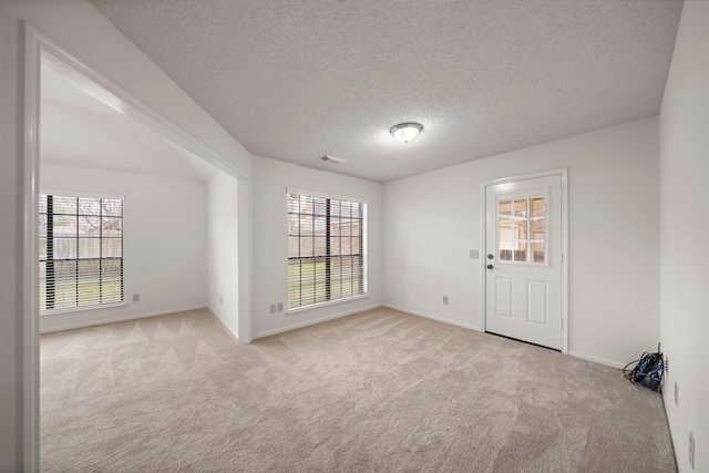 carpeted empty room with baseboards, visible vents, and a textured ceiling