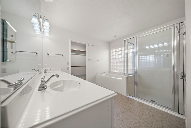 bathroom featuring a stall shower, a textured ceiling, a garden tub, and a sink