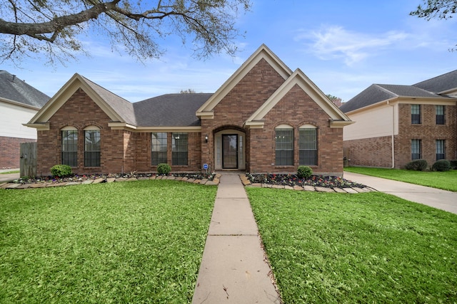 view of front of house featuring a front yard, brick siding, and a shingled roof