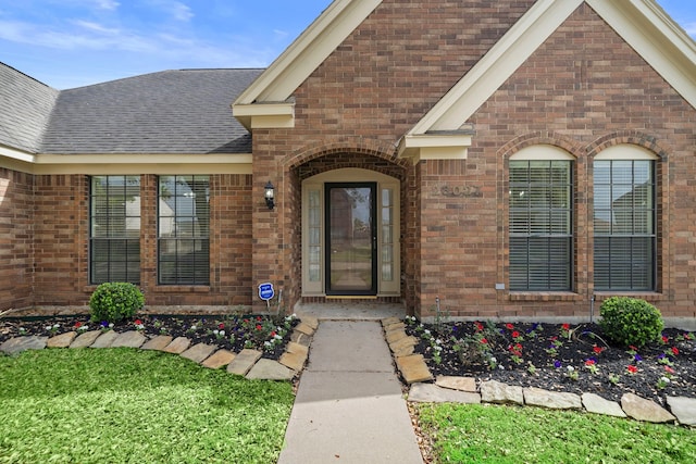 property entrance featuring brick siding and roof with shingles