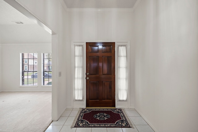 foyer entrance with light tile patterned floors, visible vents, and crown molding