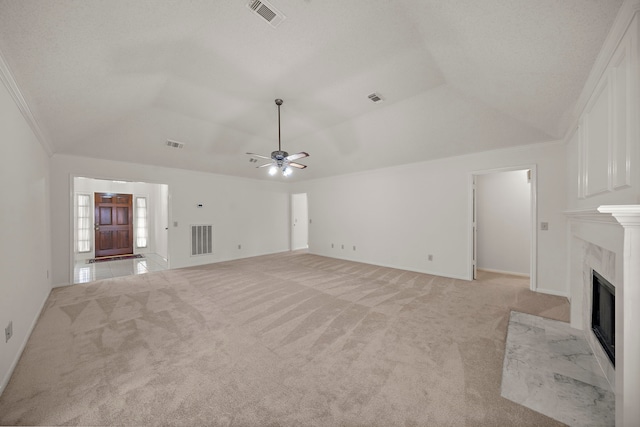 unfurnished living room featuring visible vents, ornamental molding, a high end fireplace, lofted ceiling, and light colored carpet