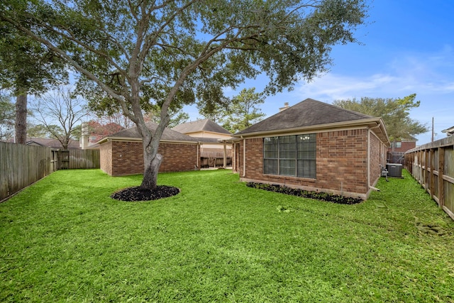 rear view of house featuring central AC unit, a fenced backyard, an outdoor structure, a lawn, and brick siding