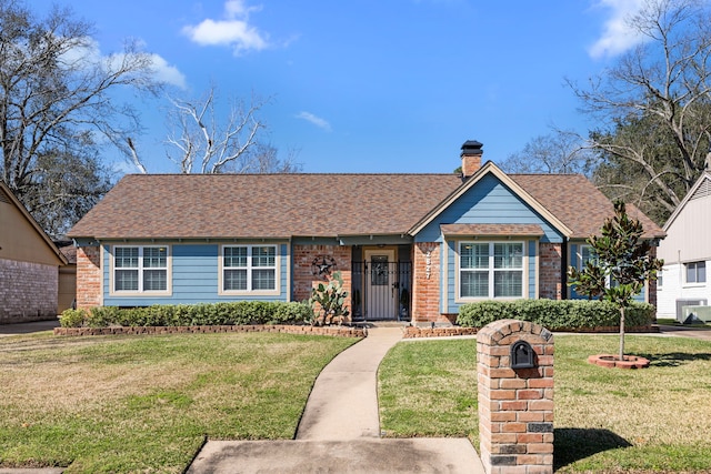 ranch-style home featuring brick siding, a chimney, a front yard, and a shingled roof