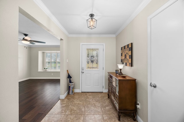 tiled entryway featuring ceiling fan, baseboards, and ornamental molding