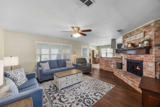 living room featuring visible vents, a brick fireplace, ceiling fan, and wood-type flooring