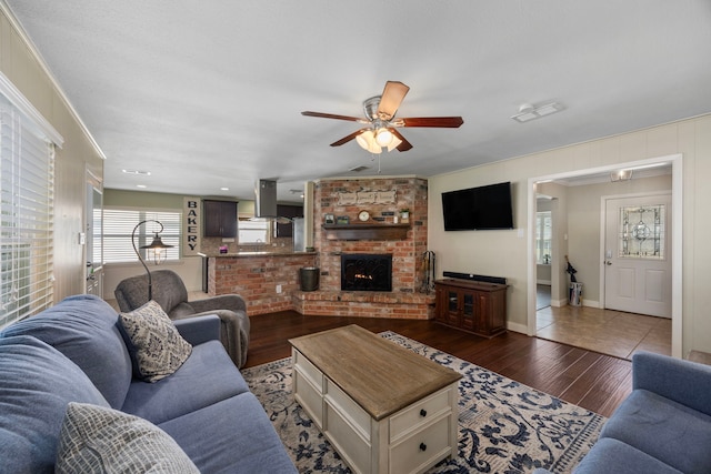 living room with visible vents, a ceiling fan, wood finished floors, a fireplace, and baseboards