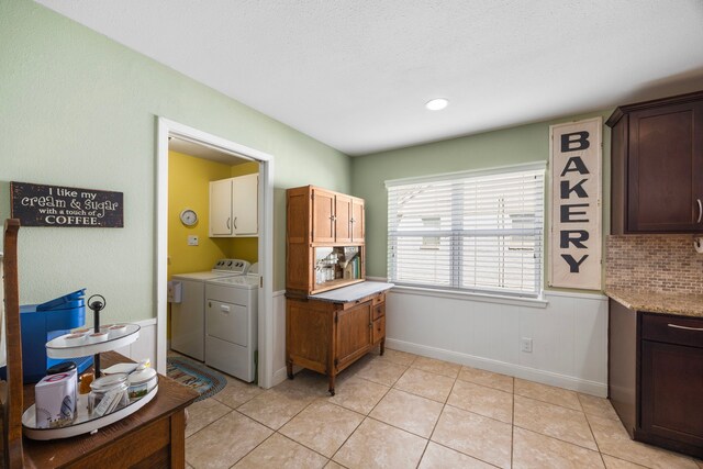 washroom featuring light tile patterned floors, cabinet space, independent washer and dryer, and baseboards