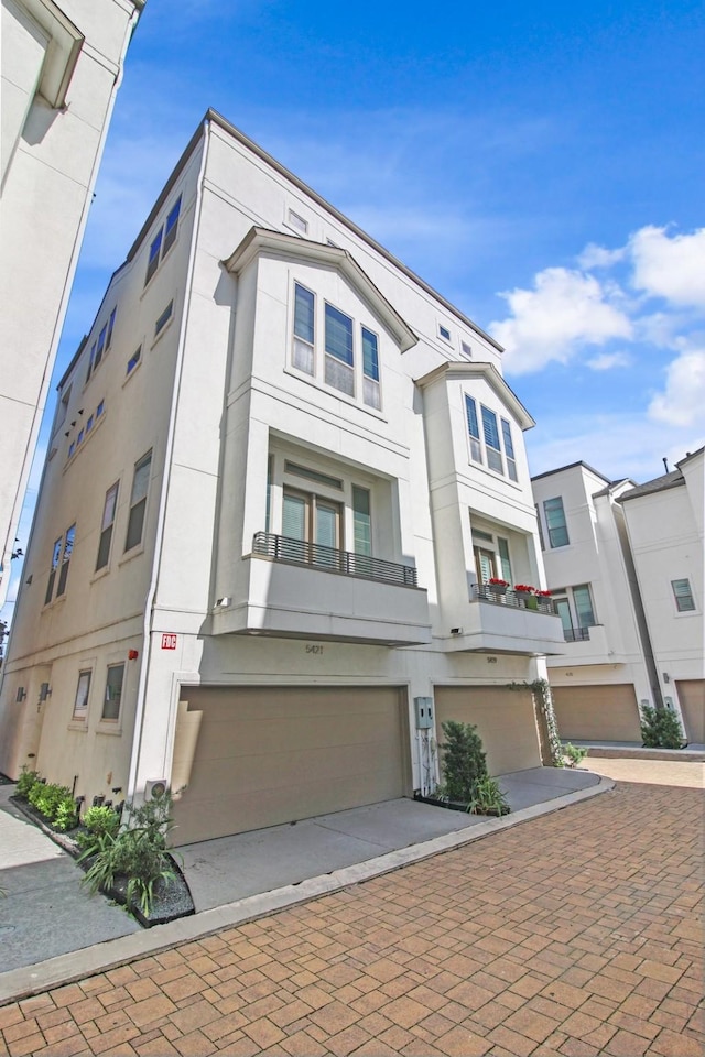 townhome / multi-family property featuring decorative driveway, an attached garage, and stucco siding