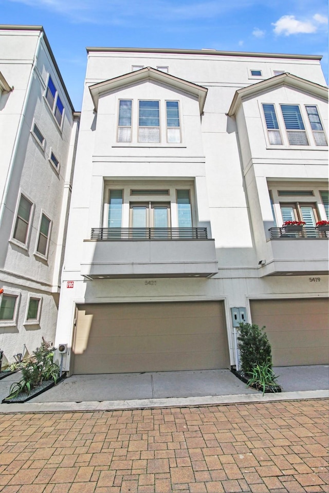 townhome / multi-family property featuring decorative driveway, an attached garage, and stucco siding