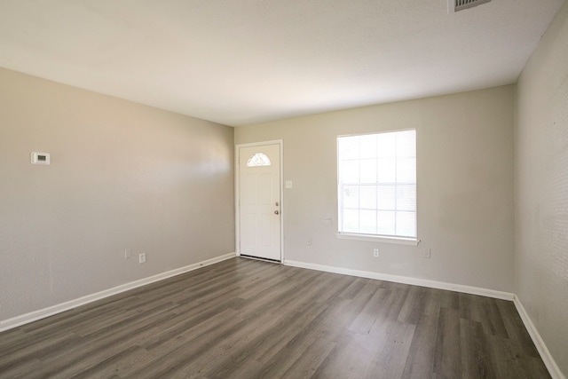 foyer with dark wood-type flooring, visible vents, and baseboards