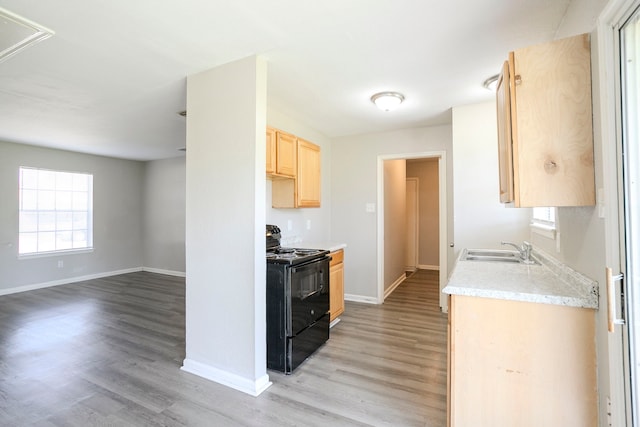 kitchen featuring light wood finished floors, black range with electric cooktop, light brown cabinetry, light countertops, and a sink