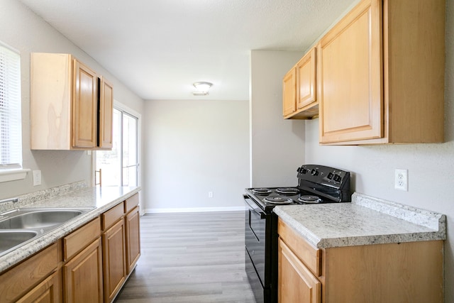 kitchen featuring electric range, light brown cabinets, wood finished floors, light countertops, and baseboards