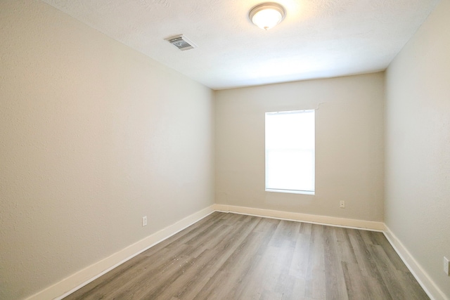 empty room featuring light wood-style floors, visible vents, and baseboards