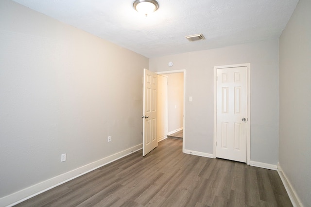 unfurnished bedroom featuring visible vents, wood finished floors, baseboards, and a textured ceiling