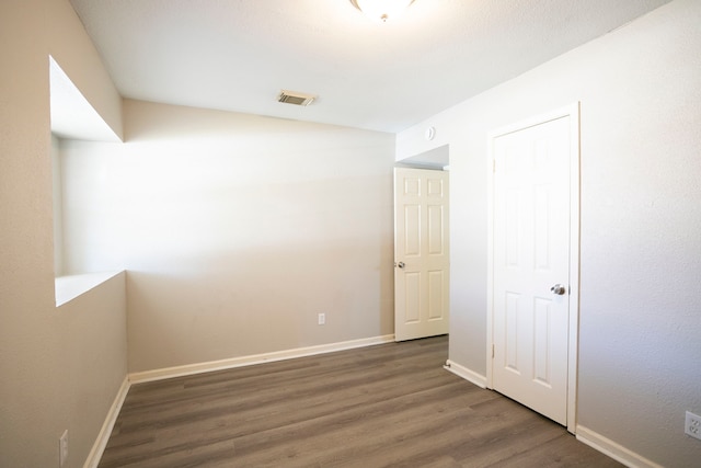 empty room featuring visible vents, wood finished floors, and baseboards