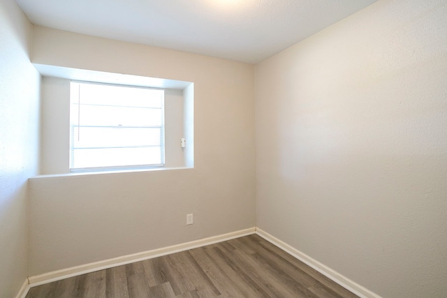 spare room with baseboards and wood finished floors