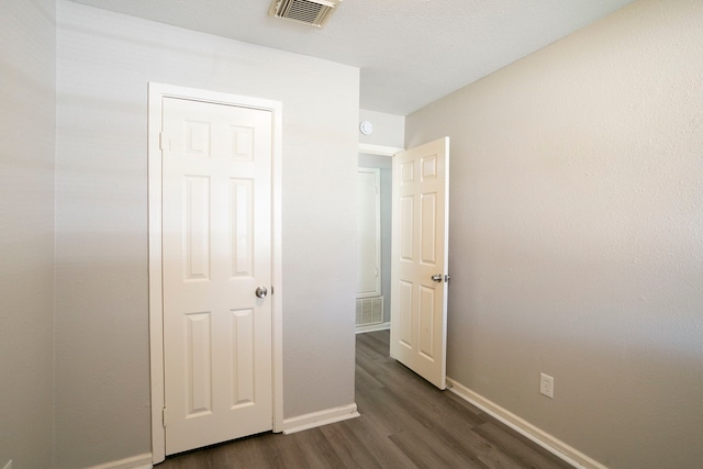 unfurnished bedroom featuring visible vents, baseboards, and dark wood-style floors