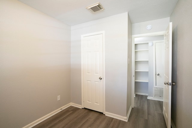 unfurnished bedroom with visible vents, baseboards, and dark wood-type flooring