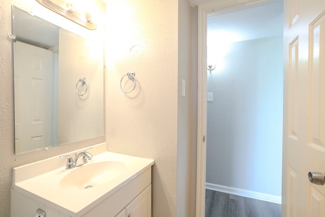 bathroom with baseboards, wood finished floors, and vanity