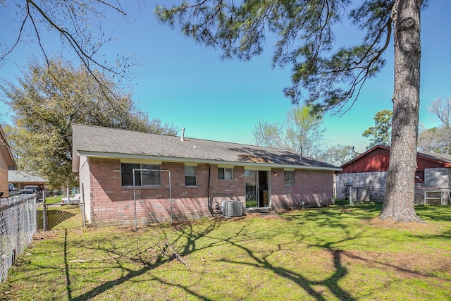 rear view of property with brick siding, central AC unit, a yard, and fence