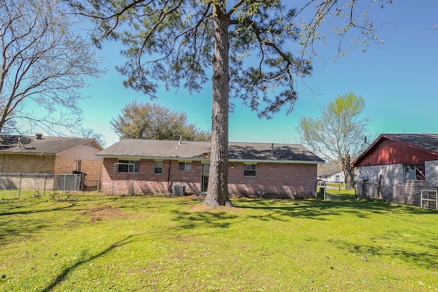 back of property featuring a yard, brick siding, central AC unit, and fence