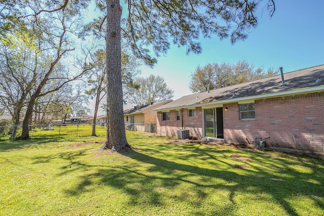 rear view of house with central AC unit, fence, and brick siding