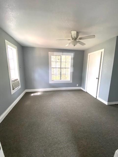 empty room featuring ceiling fan, baseboards, and dark colored carpet