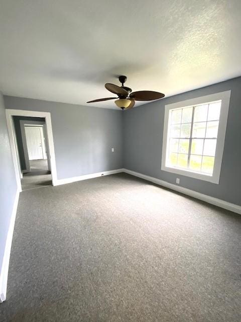 carpeted spare room featuring baseboards and a ceiling fan