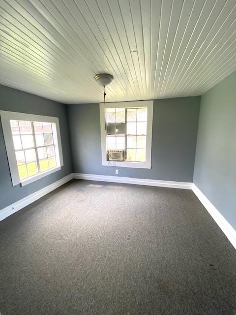 unfurnished room with wooden ceiling, cooling unit, baseboards, and dark carpet