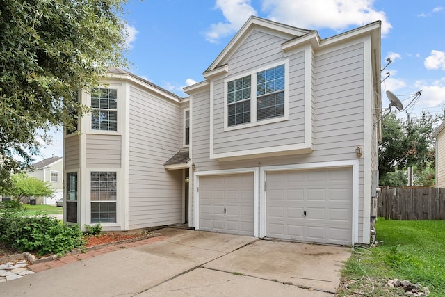 view of front of house featuring an attached garage, fence, and driveway