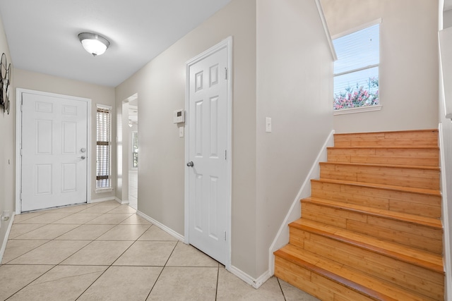 foyer entrance with light tile patterned floors, stairway, baseboards, and a wealth of natural light