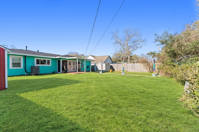 view of yard with central air condition unit and fence