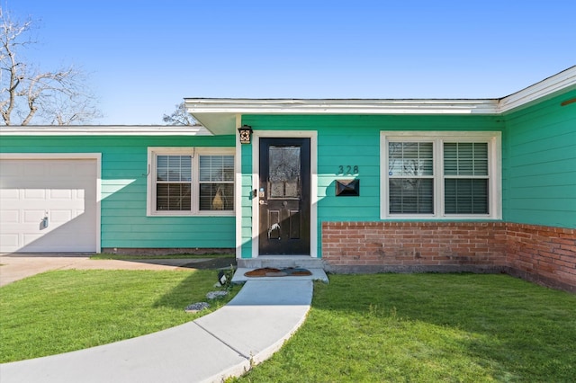 doorway to property with a yard, brick siding, and a garage