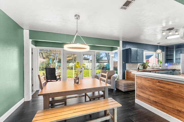 dining area featuring visible vents, baseboards, french doors, a textured wall, and dark wood-style flooring