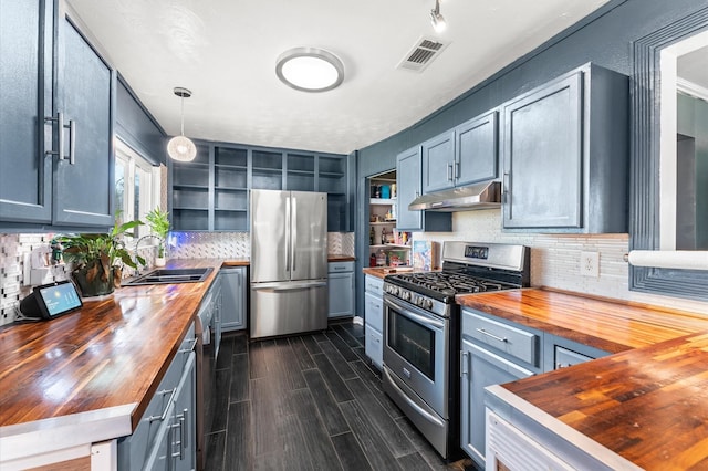 kitchen featuring under cabinet range hood, open shelves, appliances with stainless steel finishes, and butcher block counters