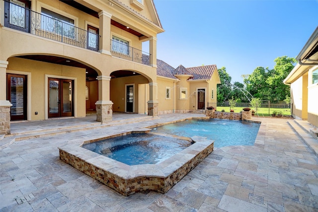 view of pool with a patio area, french doors, a pool with connected hot tub, and fence