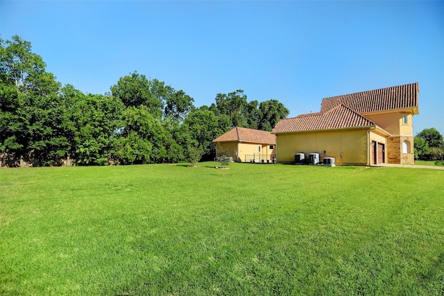 view of yard featuring central AC unit and a garage