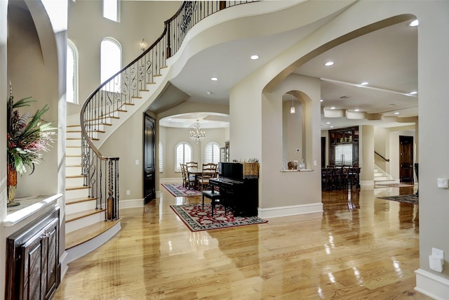 entrance foyer featuring arched walkways, stairway, baseboards, and a towering ceiling