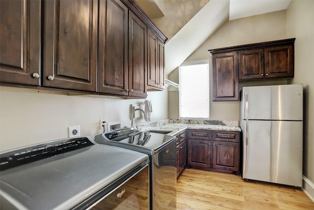 clothes washing area featuring a sink, cabinet space, light wood-style floors, and washing machine and dryer