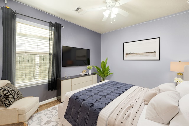 bedroom featuring visible vents, light colored carpet, baseboards, and ceiling fan