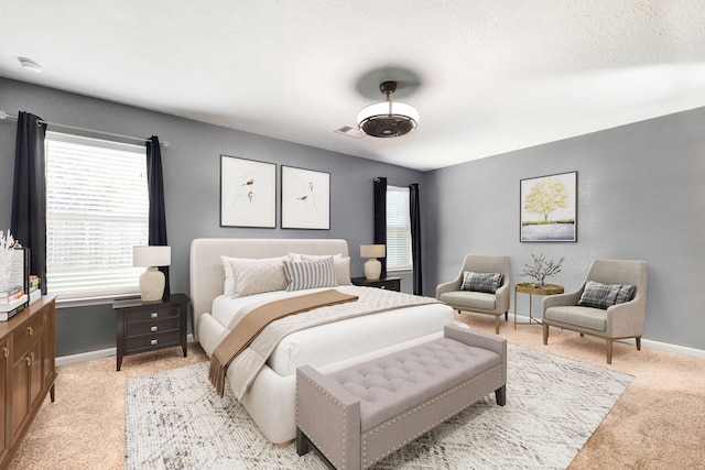 bedroom featuring baseboards, multiple windows, light carpet, and visible vents