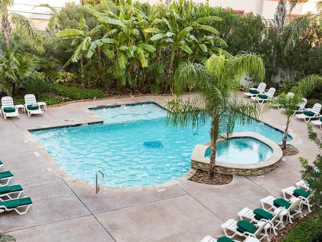 pool with a hot tub and a patio area