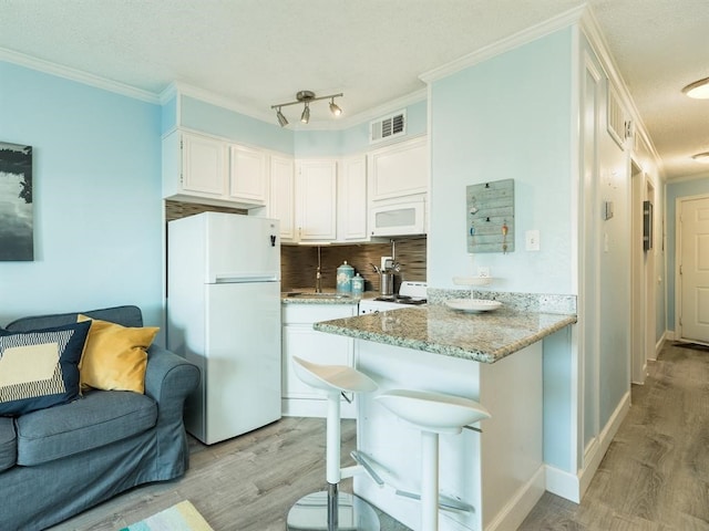 kitchen featuring white appliances, light wood finished floors, white cabinetry, crown molding, and tasteful backsplash