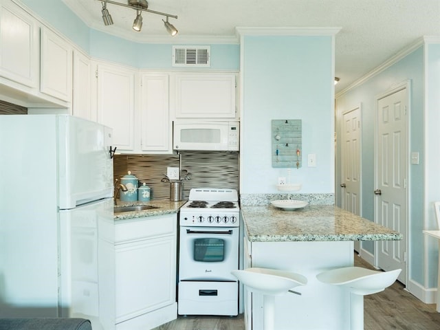 kitchen with white appliances, visible vents, a peninsula, ornamental molding, and a sink