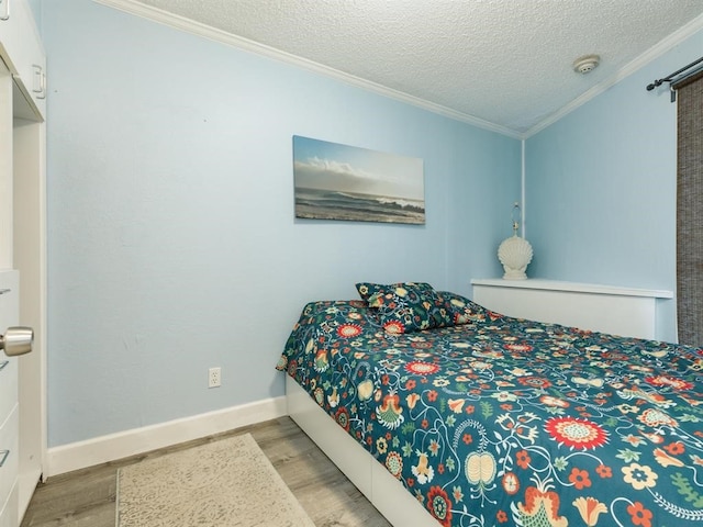 bedroom featuring a textured ceiling, crown molding, baseboards, and wood finished floors